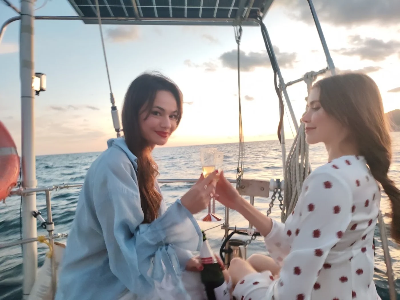Amigas brindando con cava a bordo durante la puesta de sol en velero