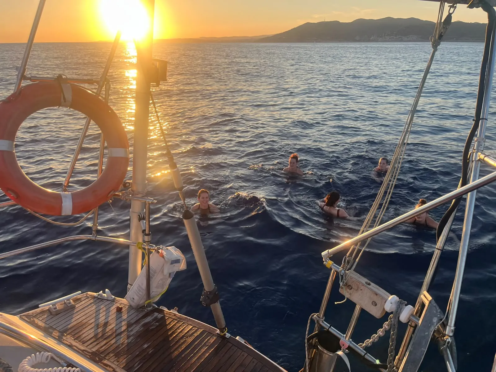 Cielo rosa y naranja sobre el mar mientras el velero navega tranquilo