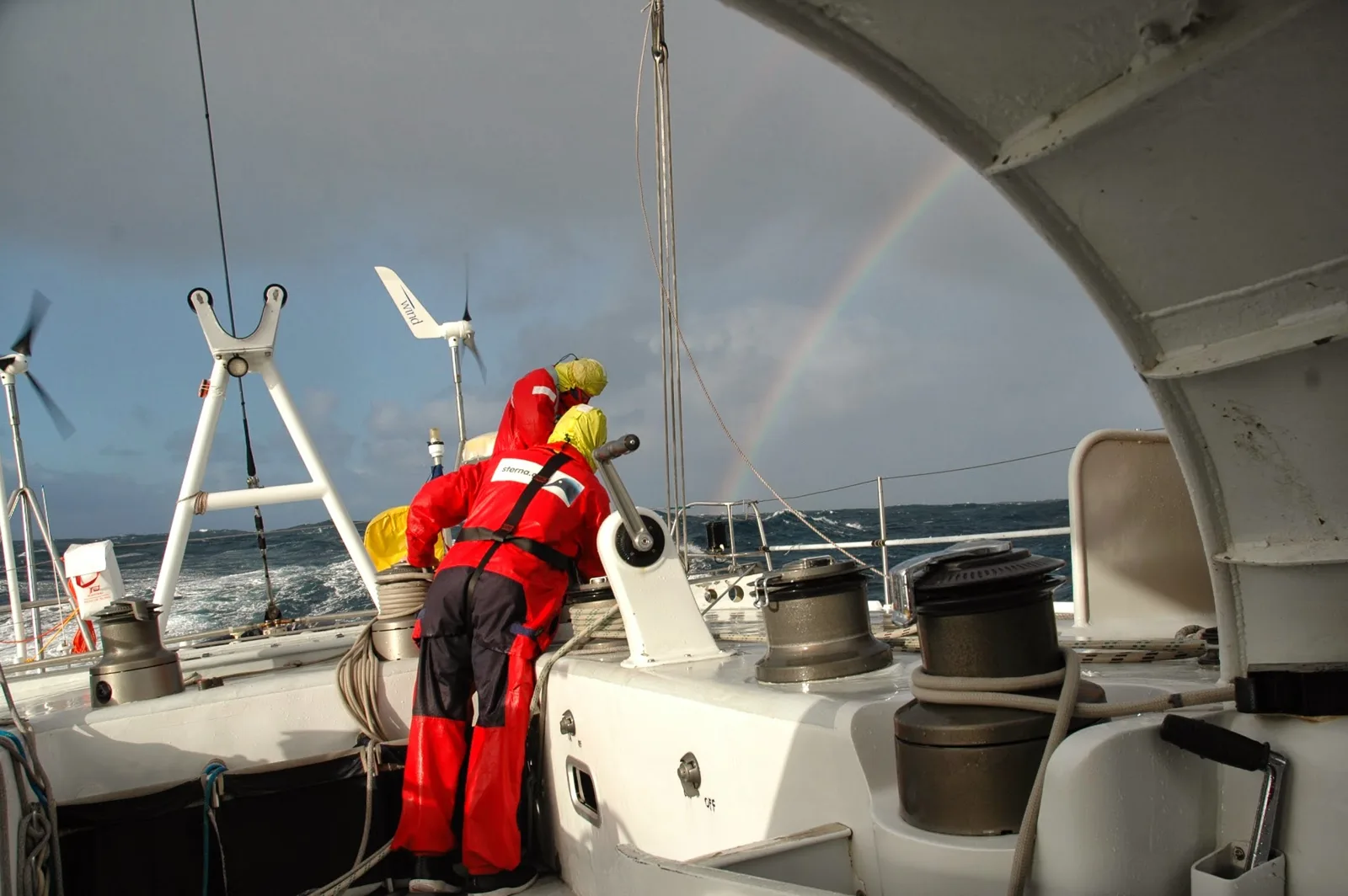 Tripulante del Sterna en cubierta con mar gruesa y un arco iris