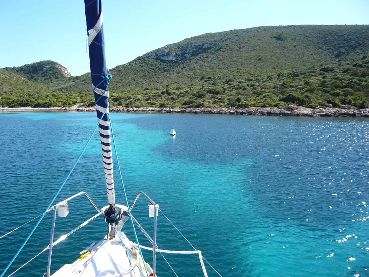 Agua turquesa vista desde la proa de un velero fondeado en Cabrera