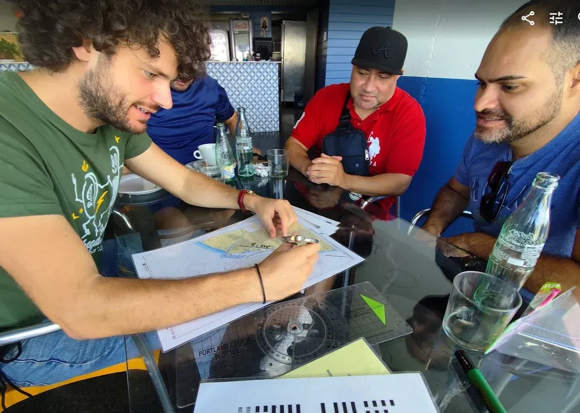 Clase de carta náutica del PER en Altair: un alumno mide sobre la carta con el compás, con el transportador sobre la mesa